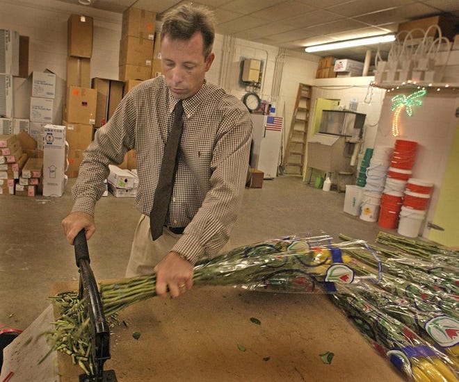 David Zeleznik, manager of Horst Wholesale Florist, trims the ends of the flowers so that the stems will accept the water better. (Steve Bisson/Savannah Morning News)