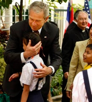 President Bush hugs a child after a group of children performed a song during his visit the Mercy Centre of the Human Development Foundation in Bangkok, Thailand Thursday, Aug. 7, 2008. Behind him at right is Mercy Centre founder Fr. Joseph Maier.