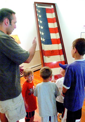 Mike Volpe of Fairport explains the story of President Lincoln’s assassination to his four sons, from left, Hudson, 3; Roman, 5; Holden, 5 and Dominick, 10, as they examine the Lincoln Flag on display at the East Bloomfield Historical Society Thursday. The flag was used to cradle the head of the dying president after he was shot.