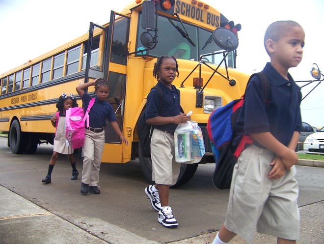 Students exit a school bus before the first day of classes at Donaldsonville Primary School Friday morning.