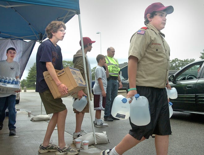 From left, Boy Scouts D.J. Sheehan, 12, Chris Mazzola, 14, and Josh Lothrop, 12, distribute water to residents at Pembroke High School on Monday.