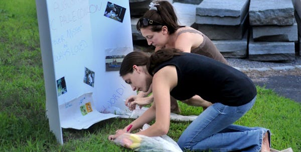 Vicky Baron, Paul Conlon’s aunt, at right, and friend Angie Williams tend to a makeshift memorial for Pfc. Paul Conlon outside their Sandwich home last night.