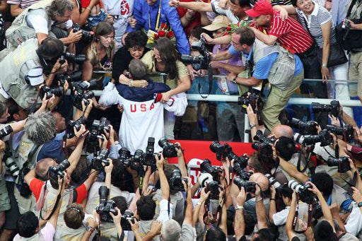 Photographers surround Michael Phelps of the United States as he is greeted by his mother Debbie and other family members after the medal ceremony for the men's 4x100-meter medley relay final, during the swimming competitions in the National Aquatics Center at the Beijing 2008 Olympics in Beijing, Sunday, Aug. 17, 2008. Phelps won his record eighth gold medal in the 400 relay, breaking a tie with Mark Spitz for the most gold medals in a single Olympics.