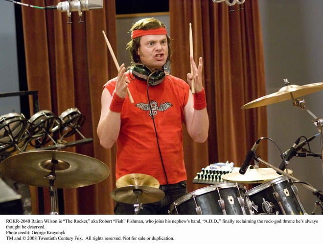 Rainn Wilson is Robert “Fish” Fishman, the former drummer for an eighties ’80s hair band, in “The Rocker.”