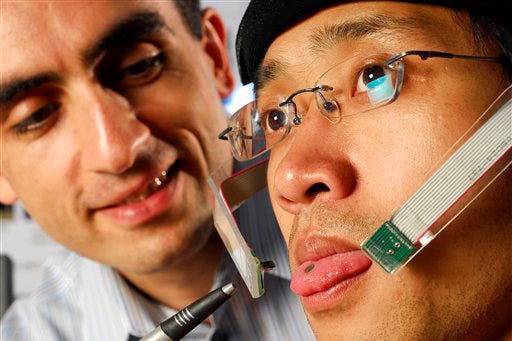 In this photo released by Georgia Tech Maysam Ghovanloo, a Georgia Tech assistant professor, points to a tiny magnet on graduate student Xueliang Huo's tongue Tuesday, June 9, 2008 in Atlanta. The device will turn Huo's tongue into a joystick that controls a wheelchair and the team hopes it could help the disabled gain more mobility.
