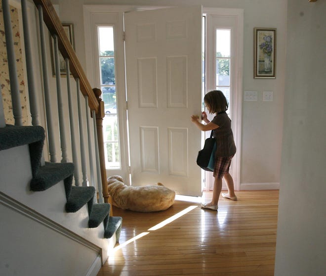 Six-year-old Emily Mortimer moves the family dog, Chamois, away from the door as she heads outside to wait for the bus outside her Raynham home on Tuesday morning in preparation for her first day of first grade.