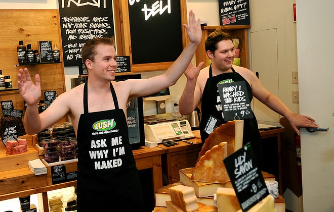 Ross Higgins, left, manager of Lush Fresh Handmade Cosmetics in the Natick Collection, and assistant manager Steve Zastawny enter the store wearing just sandals, briefs and an apron.