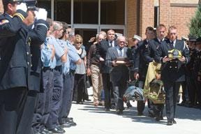 CHIEFTAIN PHOTO/CHRIS McLEAN — Mourners carry firefighter William 'Billy' Pine's uniform and his remains from Praise Assembly of God Church following his funeral service Wednesday morning. The Pueblo firefighter died after a bout with cancer.