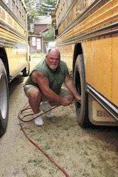 Dave Kemp, transportation supervisor at Mendon Community Schools, checks air pressure in the buses as he prepares for the start of the school year on Tuesday. Like many local supervisors, Kemp tries to go beyond simple measures to save the district money.