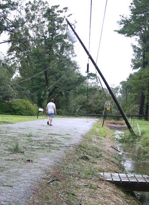 Danny LaPorte surveys damage as a power poll hangs on Bourque Road off Hwy. 621 Monday.