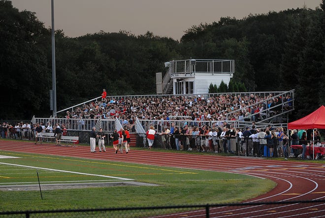 A crowd gathers Sunday evening in the grandstands of the football field at Holliston High School for a candlelight vigil for 16-year-old Joseph Larracey, who died Friday night.
