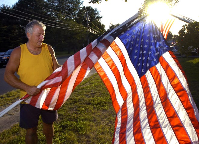 West Bridgewater highway department foreman Bill Kovatis carefully rolls up an American flag in 2005 that had been used in the annual display that commemorates the Sept. 11 tragedy.