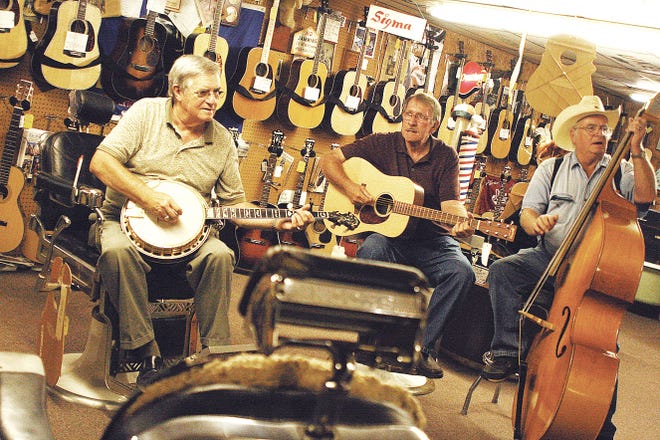 David West, owner of the Ciderville Music Barn on Clinton Highway, left, picks his banjo while sitting in barber chairs with friends Ken Bonham, of Knoxville, on guitar, and Rowdy Cope, of Claxton, on bass.