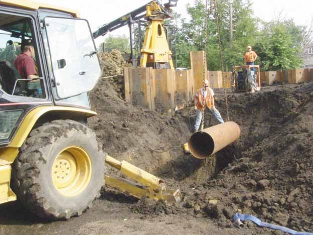 Workers lower the last section of pipe into place, as a collapsed concrete sewer under the railroad tracks on the west side of Kewanee was replaced with new iron pipe this week.