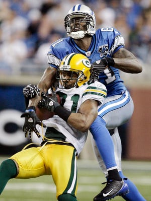 Green Bay Packers cornerback Charles Woodson, bottom, intercepts a pass intended for Detroit Lions wide receiver Calvin Johnson in the fourth quarter of an NFL football game Sunday, Sept. 14, 2008, in Detroit. The Packers beat the Lions 48-25.