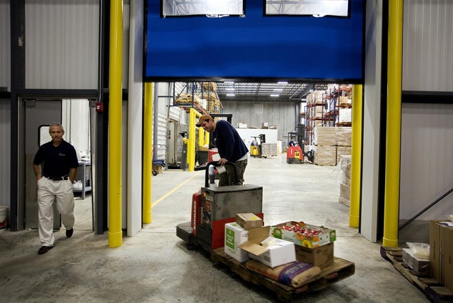 Purchase these photos at www.sj-r.com/reprints	Photographs by Shannon Kirshner/The State Journal-Register
Vice president S. David Rikas watches as Chad Baldoni carts an order through a high-speed automatic door inside the new M.J. Kellner facility on Wabash near Interstate 72.