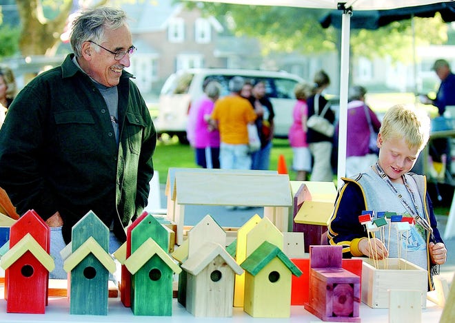 Kyrill Gill, 8, of Rochester, checks out birdhouses for sale as vendor Pete Royle of East Irondequoit looks on.