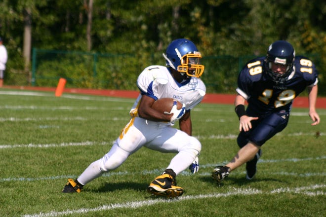 Jamar Paige of Irondequoit makes a cut to get around Webster Thomas defender Tyler Snavley (19) in action on Saturday. Paige scored three touchdowns in leading the Eagles to their first-ever win over the Titans, 42-21.