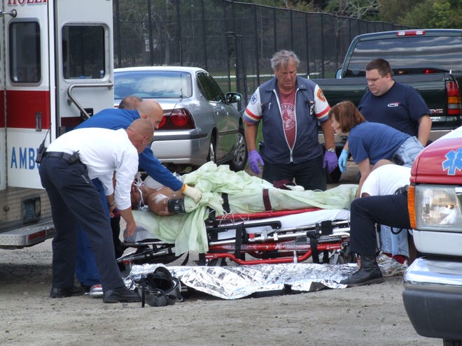 An unidentified man is moved into an ambulance by medical personnel after his truck caught fire in a Holliston parking lot Tuesday.