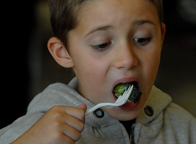 First-grader Calvin Cononi bravely tries his vegetables during lunch Tuesday at Northeast Elementary School in Waltham.