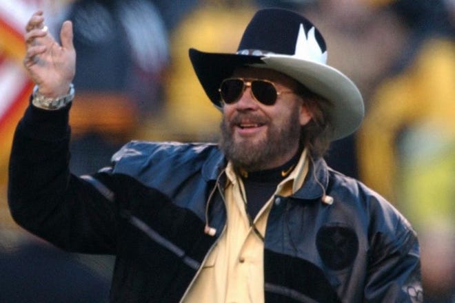 Hank Williams Jr. waves after singing the National Anthem before an AFC divisional playoff football game on Jan. 15, 2005, in Pittsburgh.