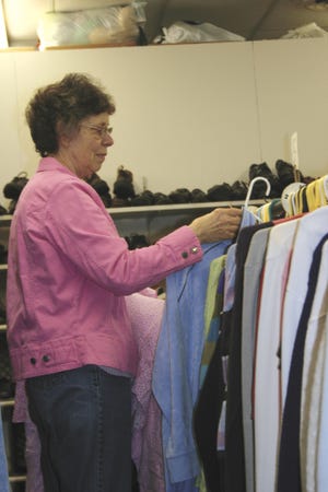 Sharon Stavenhagen, manager of the Jamieson Center Thrift Shop for more than 20 years, stocks clothes Wednesday morning. Thrift shops such as the Salvation Army and Goodwill report a 6 to 15 percent climb in sales in the last year.