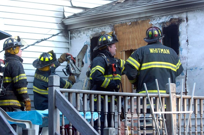 Whitman firefighters ventilate the rear of the house at a fire on School Street in Whitman.