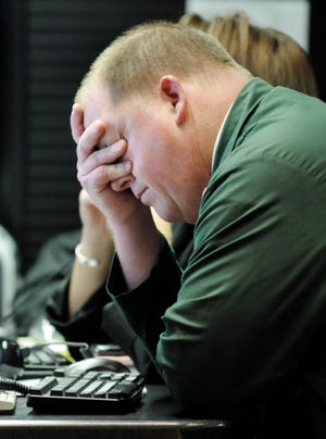 Trader Kevin McCarthy holds his head as he works on the floor of the New York Stock Exchange, Thursday Oct. 9, 2008. Stocks plunged in the final minutes of trading Thursday, sending the Dow Jones industrials down more than 675 points, or more than 7 percent, to their lowest level in five years after a major credit ratings agency said it was considering cutting its rating on General Motors Corp. (AP Photo/Richard Drew)