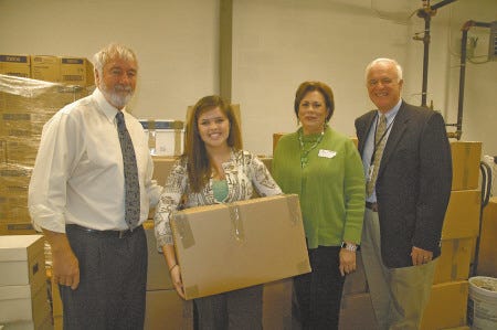 Exeter High School Junior Emily Bergan holds a box of books from the pallets being sent to South Africa. She is pictured with, from left, EHS Assistant Principal Walter Garland, ECIO founder Jan Paschal and SAU 16 Superintendent Michael Morgan.