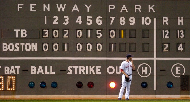 Red Sox left fielder Jason Bay stands in front of the scoreboard.