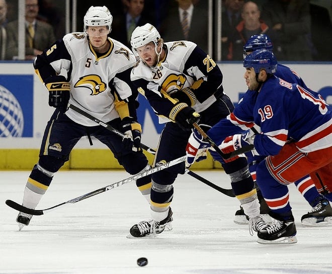 Buffalo Sabres defenseman Toni Lydman (5) watches as left wing Thomas Vanek (26), of Austria, knocks the puck past New York Rangers center Scott Gomez (19) during the second period of an NHL hockey game at Madison Square Garden in New York, Wednesday, Oct. 15, 2008. (AP Photo/Kathy Willens)