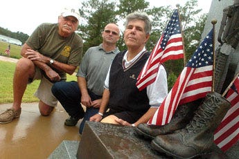 Volunteers Ed Donovan, from left, and Jim Kotyk, kneel with Thomas Russell, the founder of Step Up For Soldiers, next to the 1st of the 120th C.A.B. Fallen Soldiers Memorial at the North Carolina National Guard on Sept. 25, 2008.