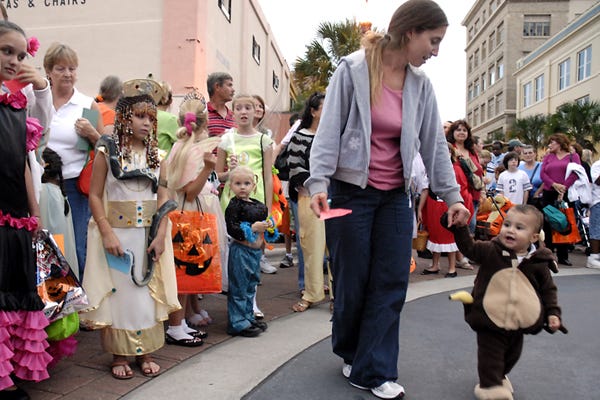 Amanda Perez, right, walks her son TobyJay Bonilla, age1, past a line of children, in costumes, and their parents prior to the costume contest during Ghouls Night Out on Saturday in downtown Winter Haven. 10/27/07