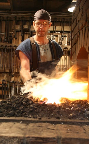 Joel Sanderson pulls a piece from his forge to begin crafting it into part for one of his many metalwork projects. Oct. 16, 2008.
