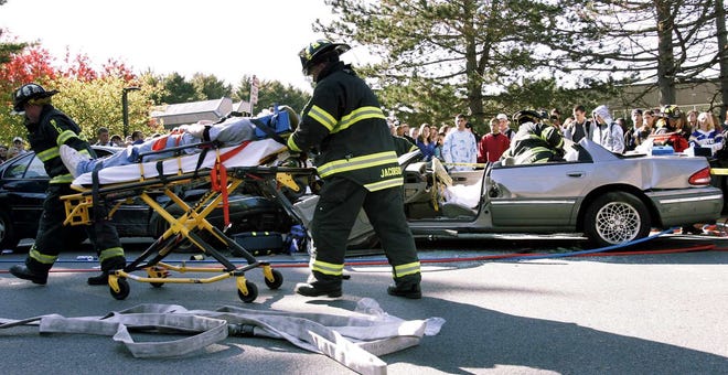 Firefighters attend to the “injured” as students look on Friday during a dramatization of a drunken driving crash at Norwell High School.