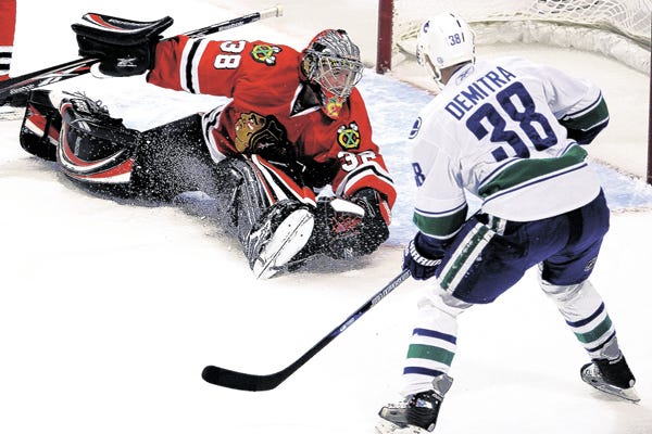 Vancouver Canucks' Pavol Demitra, right, of Slovakia, scores against Chicago Blackhawks goalie Cristobal Huet, of France, during the first period of an NHL hockey game in Chicago, Sunday, Oct. 19 2008.