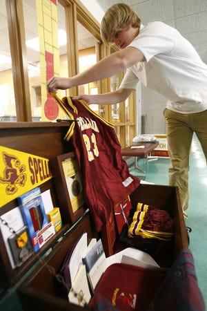 Matt Stickney, 16, of Bridgewater, a student at Cardinal Spellman, fills the new 25-year time capsule with school memorabilia inside the front lobby of the Brockton Catholic high school on Monday afternoon.