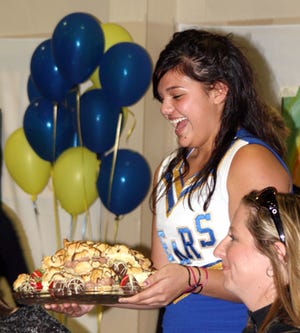 MSHS cheerleader Brandie DellaBona presents the winning bidder with a cream puff dessert, which sold for a whopping $400.