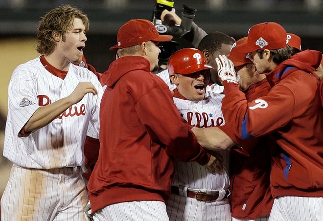Philadelphia Phillies' Carlos Ruiz, center, is congratulated by his teammates after his RBI single scoring Eric Bruntlett for the winning run during the ninth inning of Game 3 of the baseball World Series against the Tampa Bay Rays in Philadelphia, Sunday, Oct. 26, 2008. The Phillies defeated the Rays 5-4 to lead the series 2-1. (AP Photo/Gene J. Puskar)