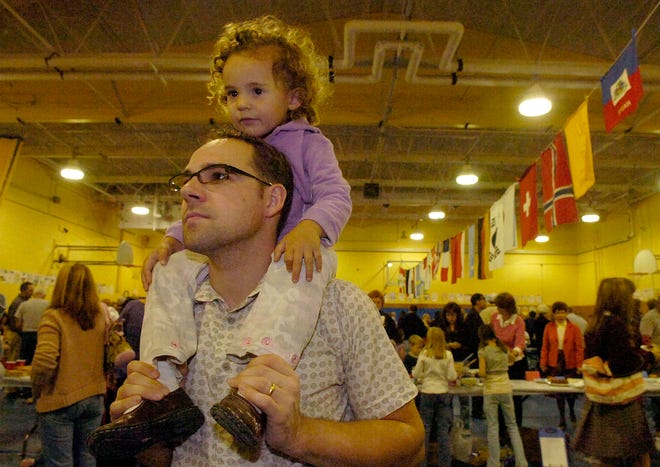 Mia Gocal, 3, rides on her dad, Mark’s, shoulders as they look at the different family shields hanging on the wall during a Celebration of Nations Gala Buffet at the LaLiberte Elementary School in Raynham last week.