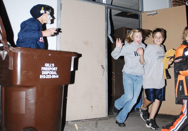 Aquin sophomore Zach Martin pops out of a garbage can and scares 12-year-old Fiona Neary, center, and 11-year-old Micah Stovall of Freeport Sunday during the Aquin Halloween Bash at Aquin Junior/Senior High School.