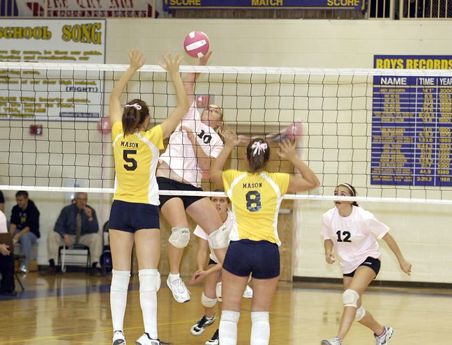 Onsted’s Ashley Tillotson hits between two Erie Mason blockers during Tuesday’s match, while Jayel Lerch (12) looks on. The Wilcats swept Erie Mason on a night “Block Cancer” night, where they held a pledge drive for donations for cancer research.