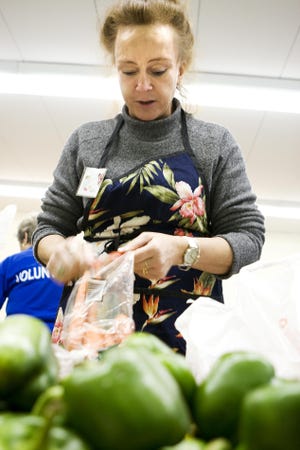 Volunteer Janice Smith of Webster opens a bag of carrots for the Tuesday night food distribution at the Webster Community Chest Food Cupboard.