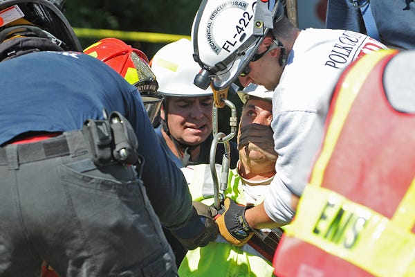 Members of the Winter Haven and Polk County fire departments lift a Verizon contract worker from a hole this afternoon at the intersection of Avenue G and First Street South in Winter Haven. A hole that was being dug collapsed on the man, and fire-rescue personnel worked a couple of hours to free him.