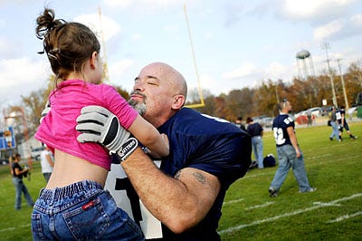 Westminster College linebacker Bob Schembre picks up his granddaughter Jayden Dennis, 4, after his final home game, a 29-27 loss to Greenville on Saturday in Fulton. Schembre and his family met on the field after the game. Schembre, 52, is a third-string linebacker for the Blue Jays. He didn't play in high school, joined the Navy, got into drugs, had a religious conversion and became a minister. His two sons played at Westminster, and he decided to pursue his dream and join the team. Â?Â  See the Slide Show