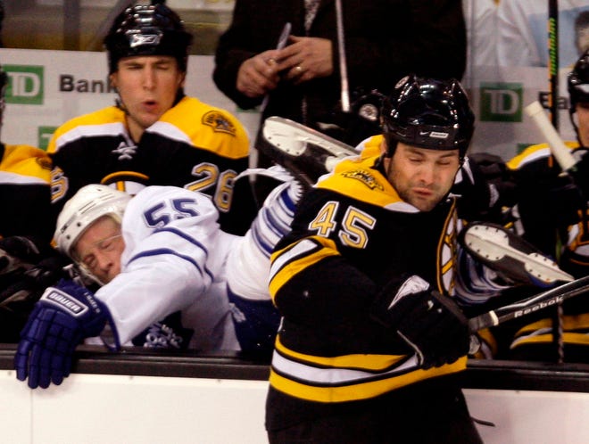 Boston Bruins defenseman Mark Stuart (45) dumps Toronto Maple Leafs left wing Jason Blake (55) into the Bruins' bench on a hard check during the first period Thursday night.