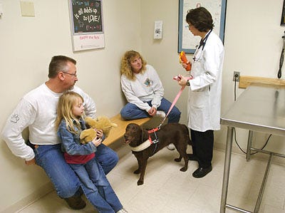 Veterinarian Deborah Fine holds rescue dog Molly's leash while talking to Allen and Alicia Brown and their daughter Allison, 5, this morning at MU's College of Veterinary Medicine. Molly was there for a checkup after receiving a pacemaker.