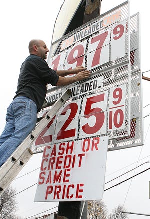 After learning that a competitor on the same street has lowered the price in the previous five minutes, Nabil Nakhoul hurries up a ladder to drop his price from $1.99 to $1.97 on Friday. Nakhoul is the owner of Molloy's Service Center on Rte. 140 in Franklin.