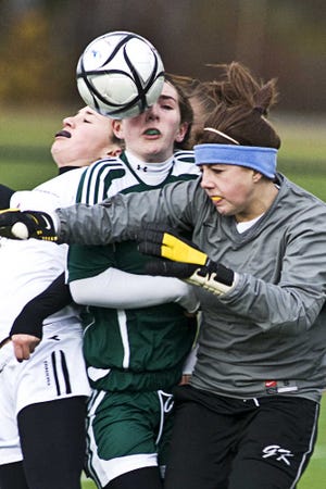 Above, from left, Algonquin’s Sam Friday, Wachusett’s Nina Hazelton and Mountaineer keeper Lauren Martin collide while jumping for a ball in front of the Wachusett net. Below, the Tomahawks’ Sarah Dahlstrom gets a congratulatory hug from a coach.