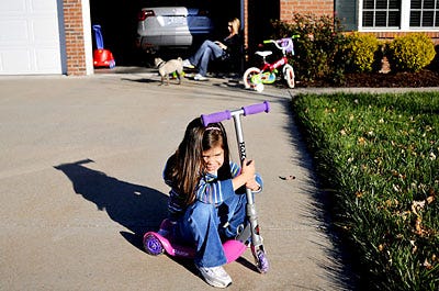 Claire Taylor, 4, takes a rest on her scooter yesterday while she plays outside her home in the Thornbrook subdivision in south Columbia. Her mom, Corie, reads a book with the family dog Zoe at her feet. The three were outside enjoying the warm weather before a cold snap moved into the area. Yesterday's high reached 60 degrees, and today's high was expected to reach only 36 degrees.